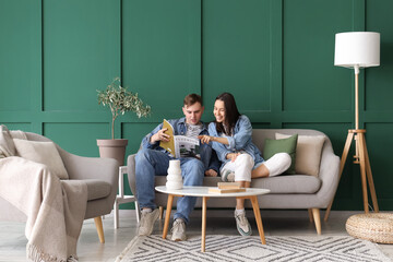 Young couple reading magazine on grey sofa in living room