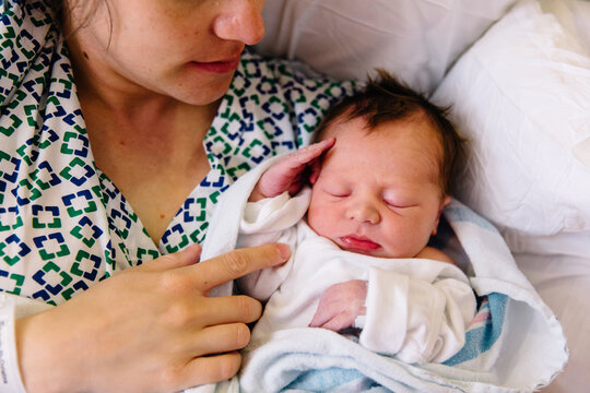 Mother holding newborn baby in hospital bed