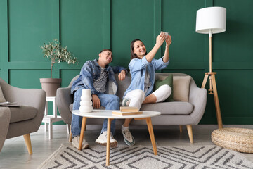 Young couple taking selfie on grey sofa in living room
