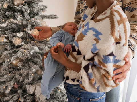 Crop diverse parents embracing near Christmas tree
