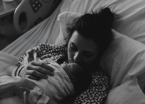 Mother tenderly kisses her newborn baby in hospital