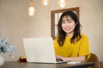 Young woman using computer at home or office, online learning, etc. Looking at camera