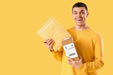 Male online store seller with parcels on yellow background