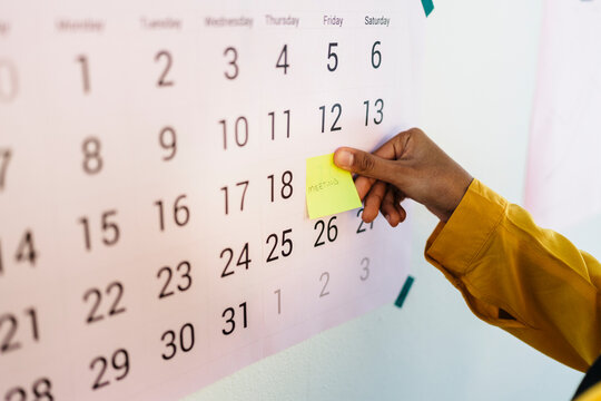 Crop executive sticking note on calendar at work
