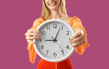 Young woman with clock on purple background, closeup