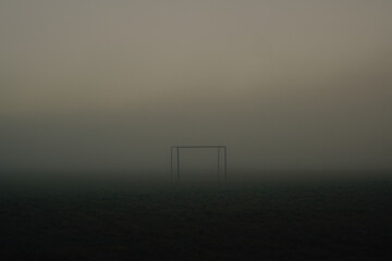 Lonely football goal standing in a foggy field.