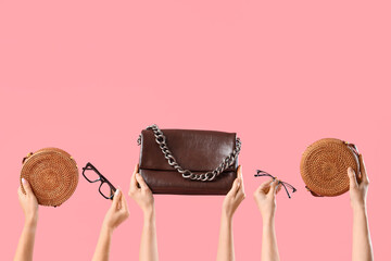 Female hands with stylish women's bags and eyeglasses on pink background