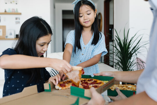 Family sharing pizza at home - Powered by Adobe