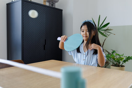 A girl playing table tennis at home