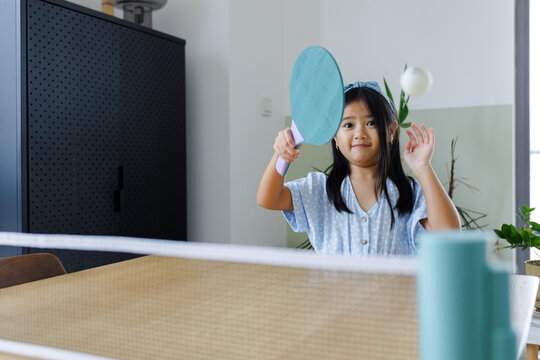 A girl playing table tennis at home