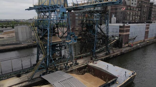 BALTIMORE - 1.19.2024 - Excellent aerial footage of a crane drawing sugar from a ship's hold to a waterfront refinery in Baltimore, Maryland.