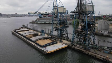 BALTIMORE - 1.19.2024 - Excellent aerial footage circling a crane collecting sugar from a ship's hold to a waterfront refinery in Baltimore, Maryland.