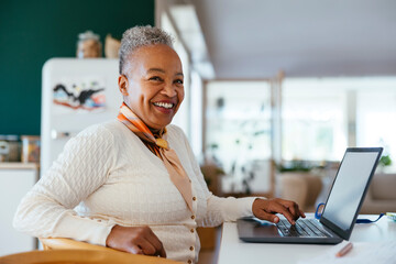 Cheerful woman working on laptop at home