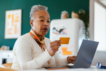Happy female with grey hair using laptop at home