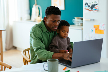 Father with kid using laptop at home