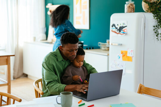 Father with kid using laptop at home