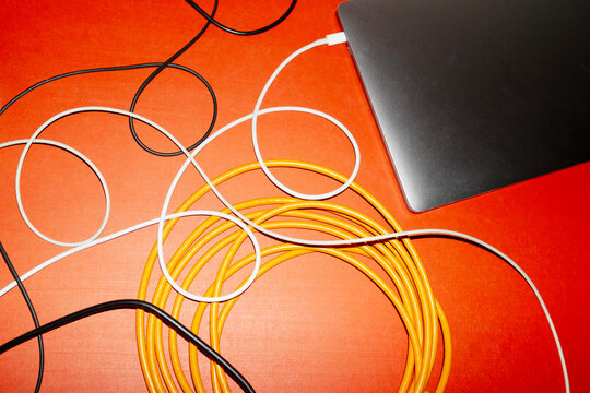 Silver laptop and colourful curve wires with hard direct flashlight