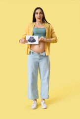 Young pregnant woman with sonogram image on yellow background