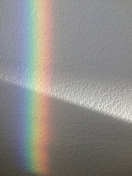 White wall with beam of light and rainbow reflection