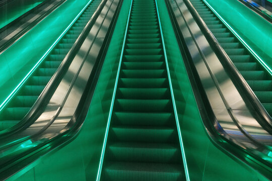 Perspective photo of escalator stairs with neon green led lights