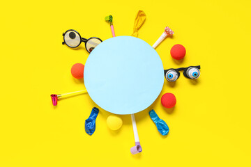Blank card with funny glasses, clown noses and party decor on yellow background. April Fools Day...