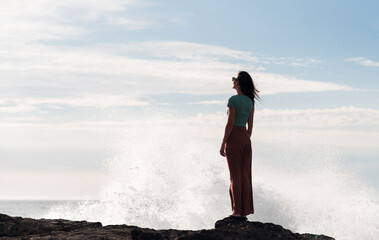 Standing woman next to big waves splash