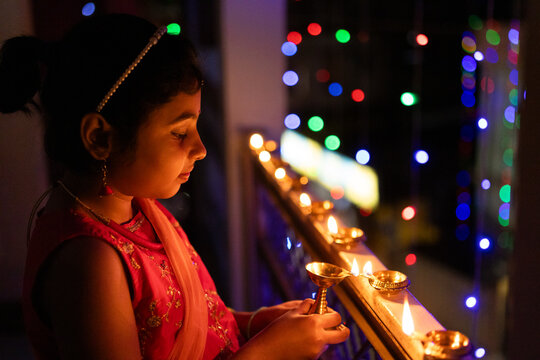 Little girl igniting oil lamps during diwali