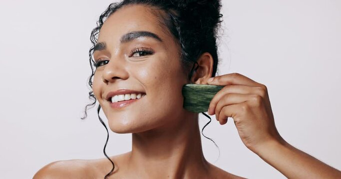 Happy, skincare and woman in studio with gua sha for facial massage, relax and beauty with glow. Dermatology, cosmetics and jade face tool for self care, smooth skin and wellness on white background