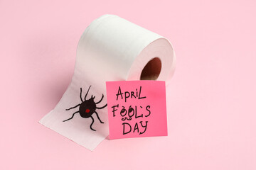 Drawing of spider on toilet paper and sticky note on pink background. April Fools Day prank