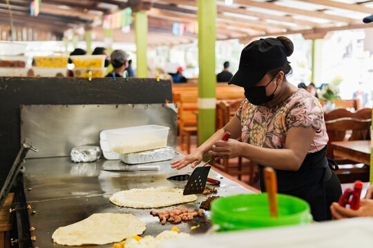 Latin woman preparing quesadillas at a market in Mexico.