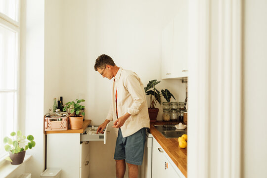 Man searching for something in kitchen drawer 
