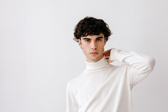Confident young man touching neck and looking at camera over