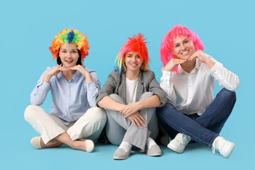 Business people in funny wigs sitting on blue background. April Fools' Day celebration