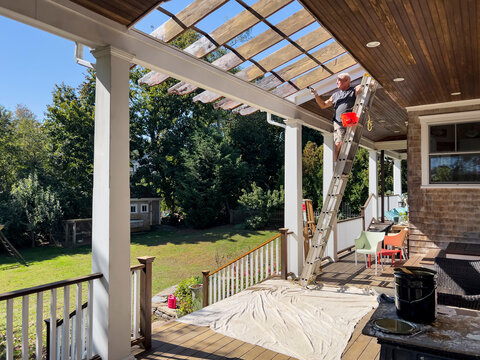 Blue Collar worker Staining wood on house maintenance 