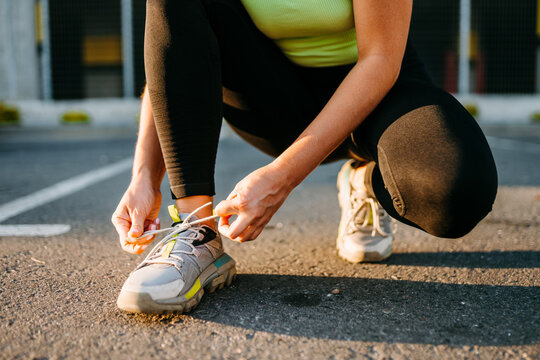 A woman ties her shoelaces during an outdoor sport