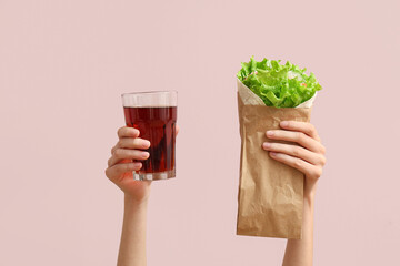 Hands with tasty doner kebab and drink on pink background