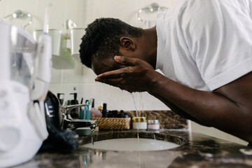 A man washing his face in the sink