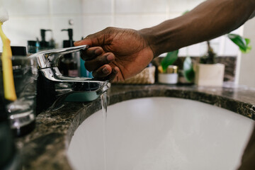 A person lifting up the tap water handle 