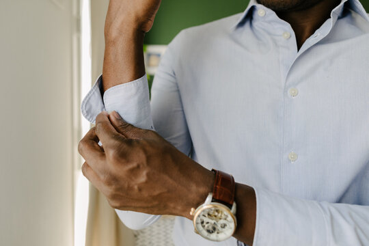 A man buttoning up his office shirt sleeve