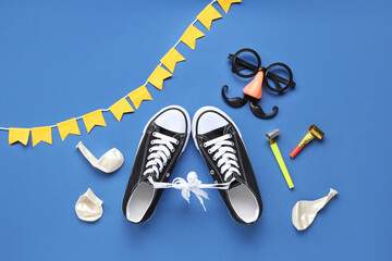 Shoes with tied together laces, funny glasses and party decor on blue background. April Fools Day...