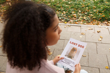 Black teen holding placard of missing dog in park
