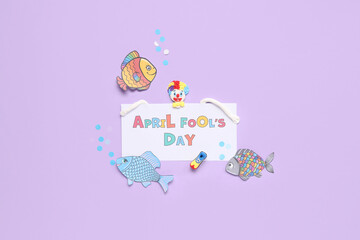 Festive postcard for April Fools Day with clown and paper fishes on lilac background