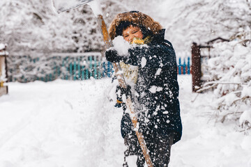 Kid Boy clearing snowy path in a suburban or countryside house yard