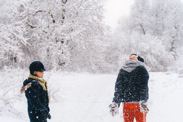 happy kids catch snowflakes in winter in a snowy forest