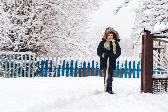 Young Boy clearing snowy path in a suburban or countryside house yard