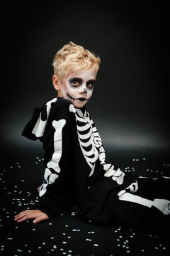 Boy in skeleton outfit for halloween, posing in a studio