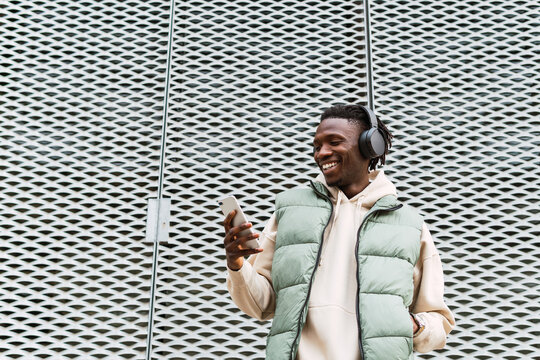 Black man with headphones browsing smartphone