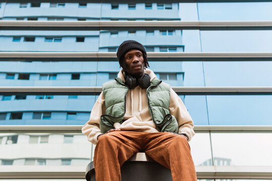 Black man in headphones near building