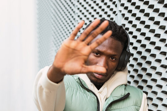 Black man showing stop gesture while listening to music