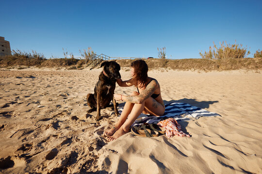 Woman sits on the beach with her dog